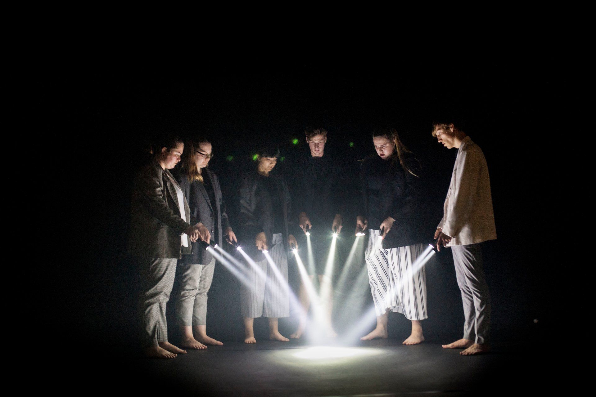 a group of people are standing in a circle holding torches in the dark .