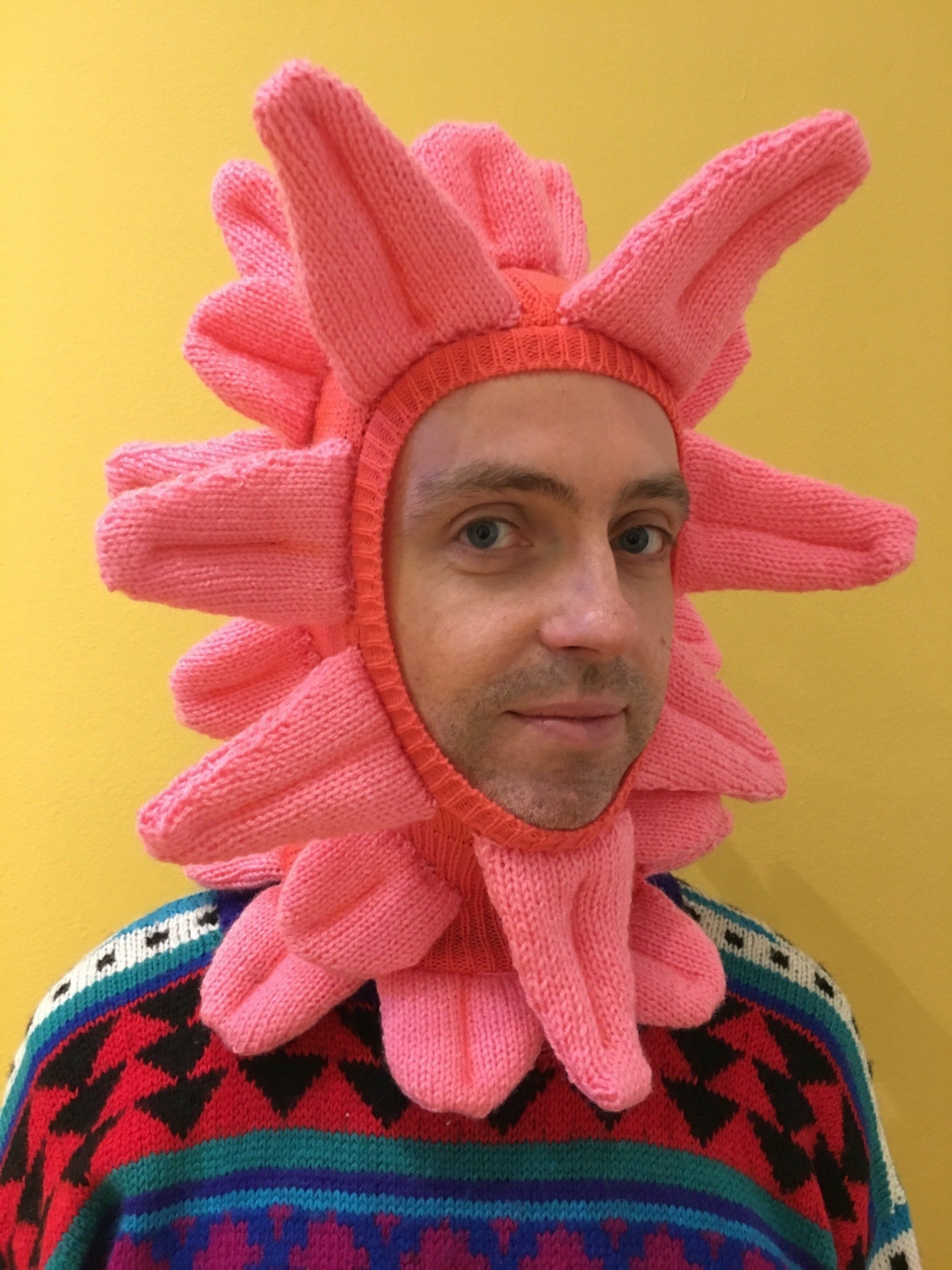 a man is wearing a pink tongue hat on his head .