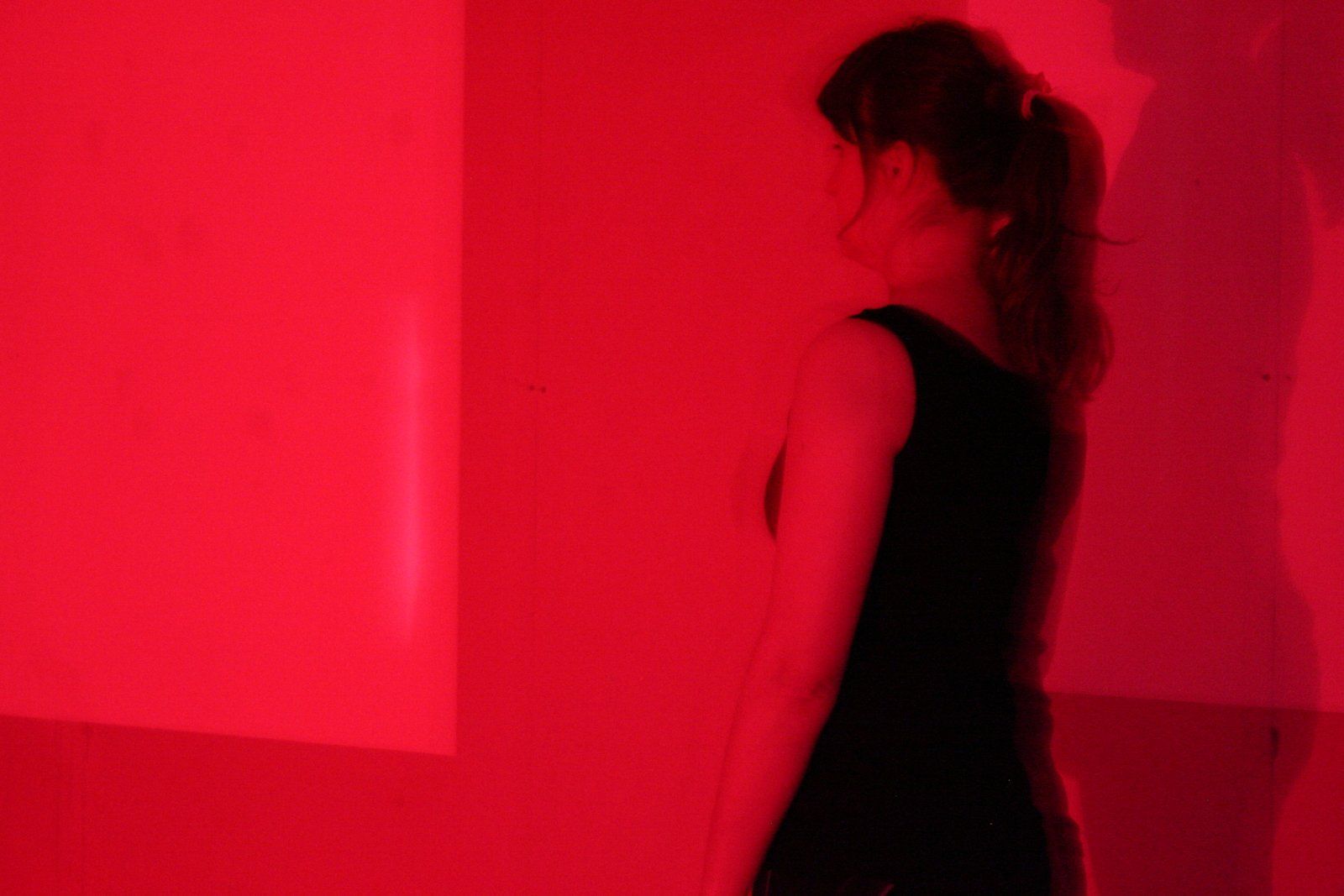 a woman in a black dress is standing in front of a red wall .