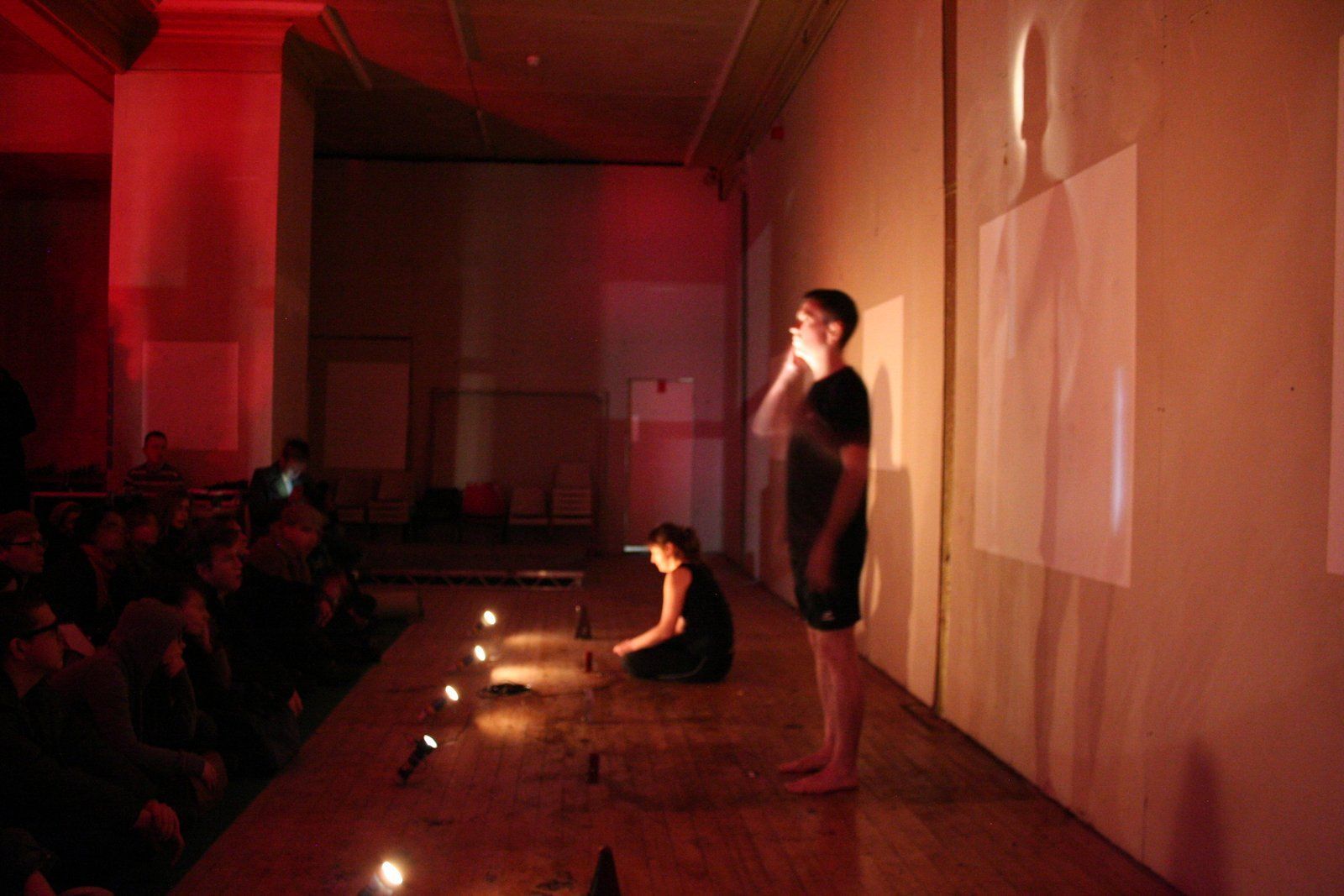 A man and a woman are standing on a stage in a dark room.