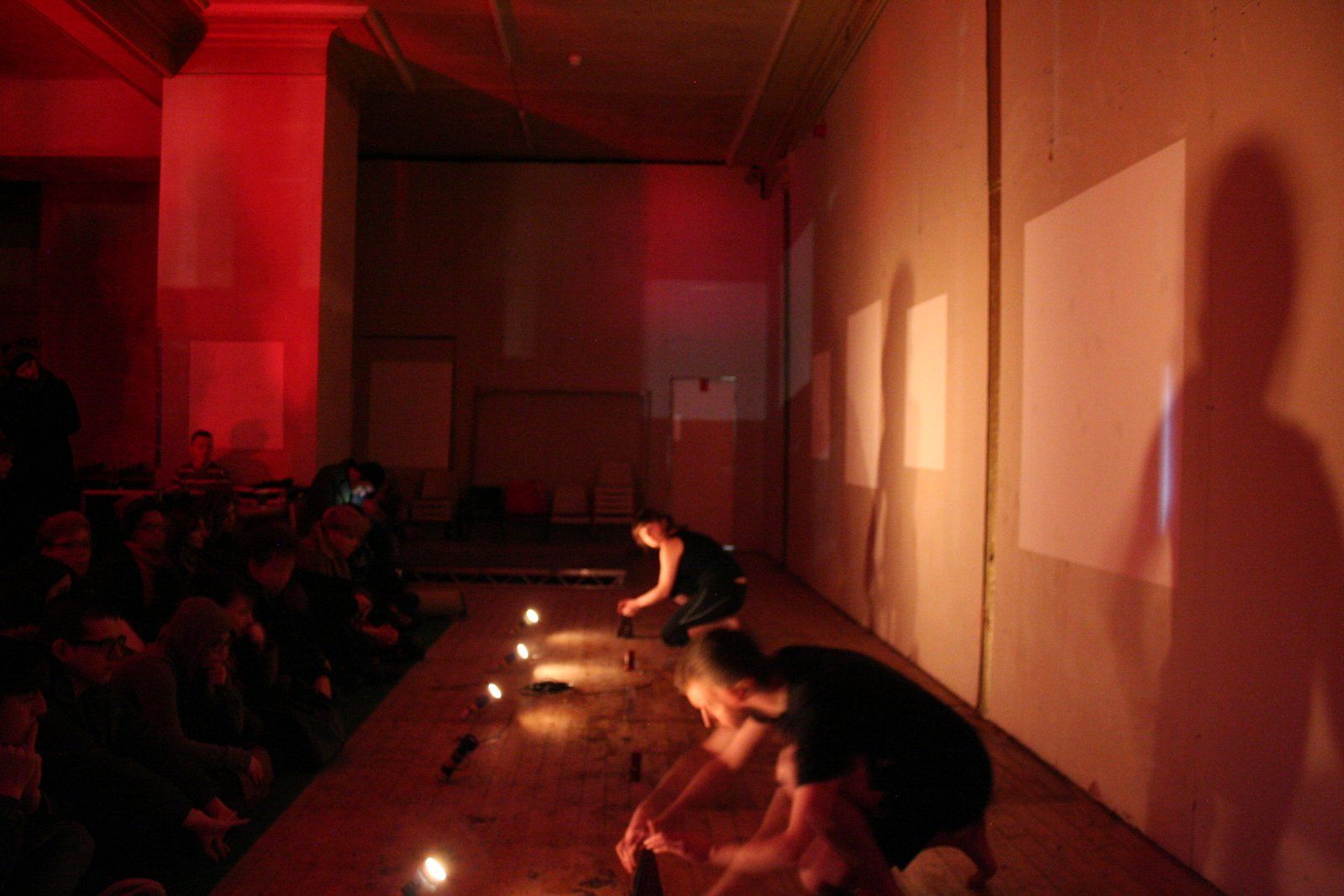 a group of people are kneeling down in a dark room with candles on the floor .