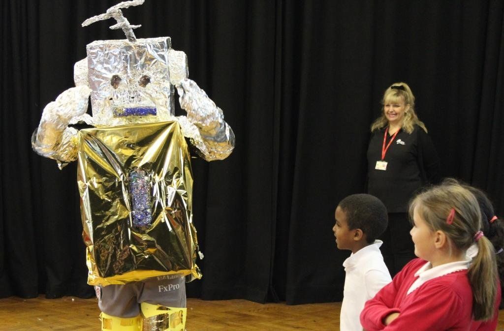 a group of children are standing around a robot costume
