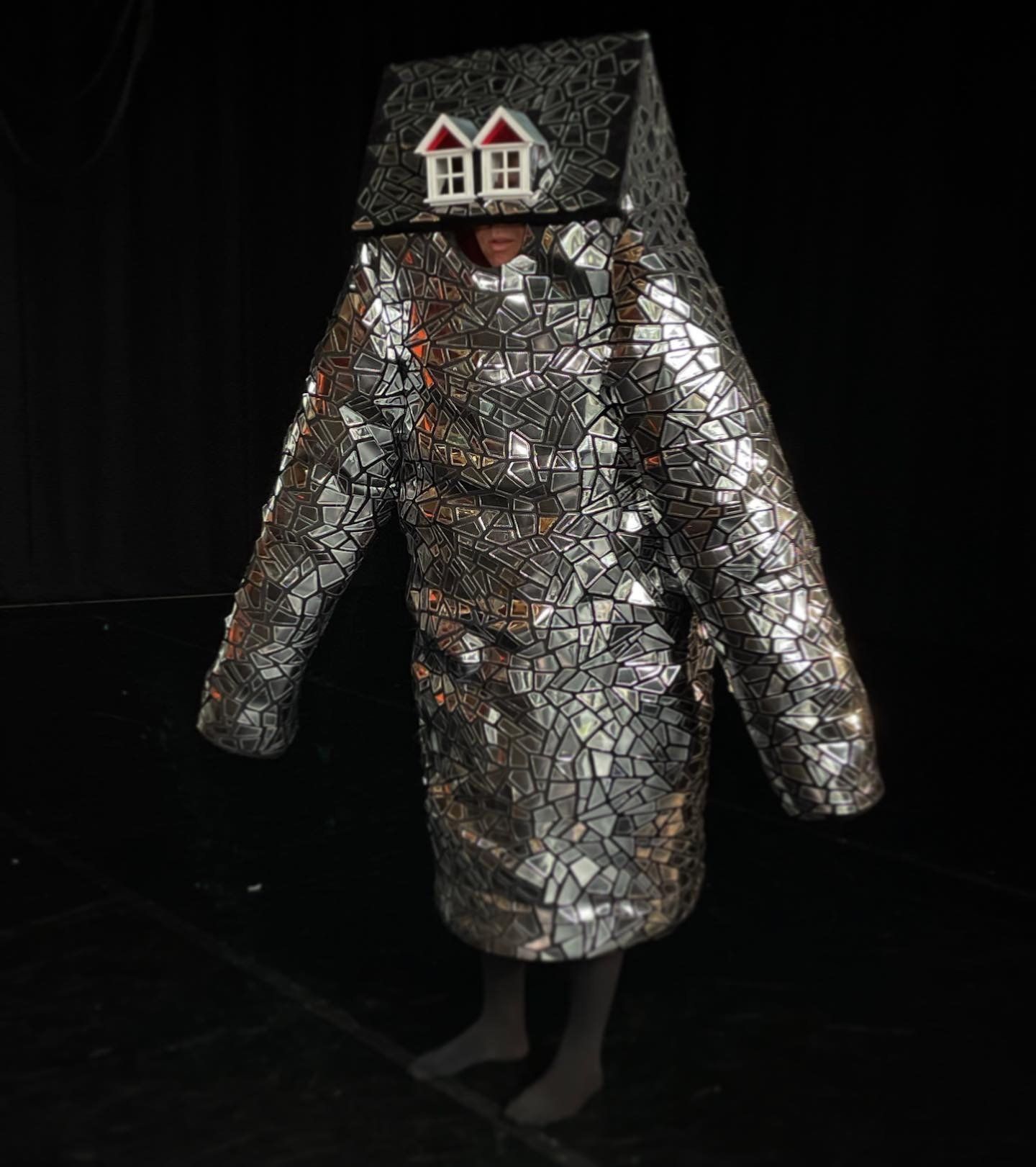 a person in a silver costume with a house on their head