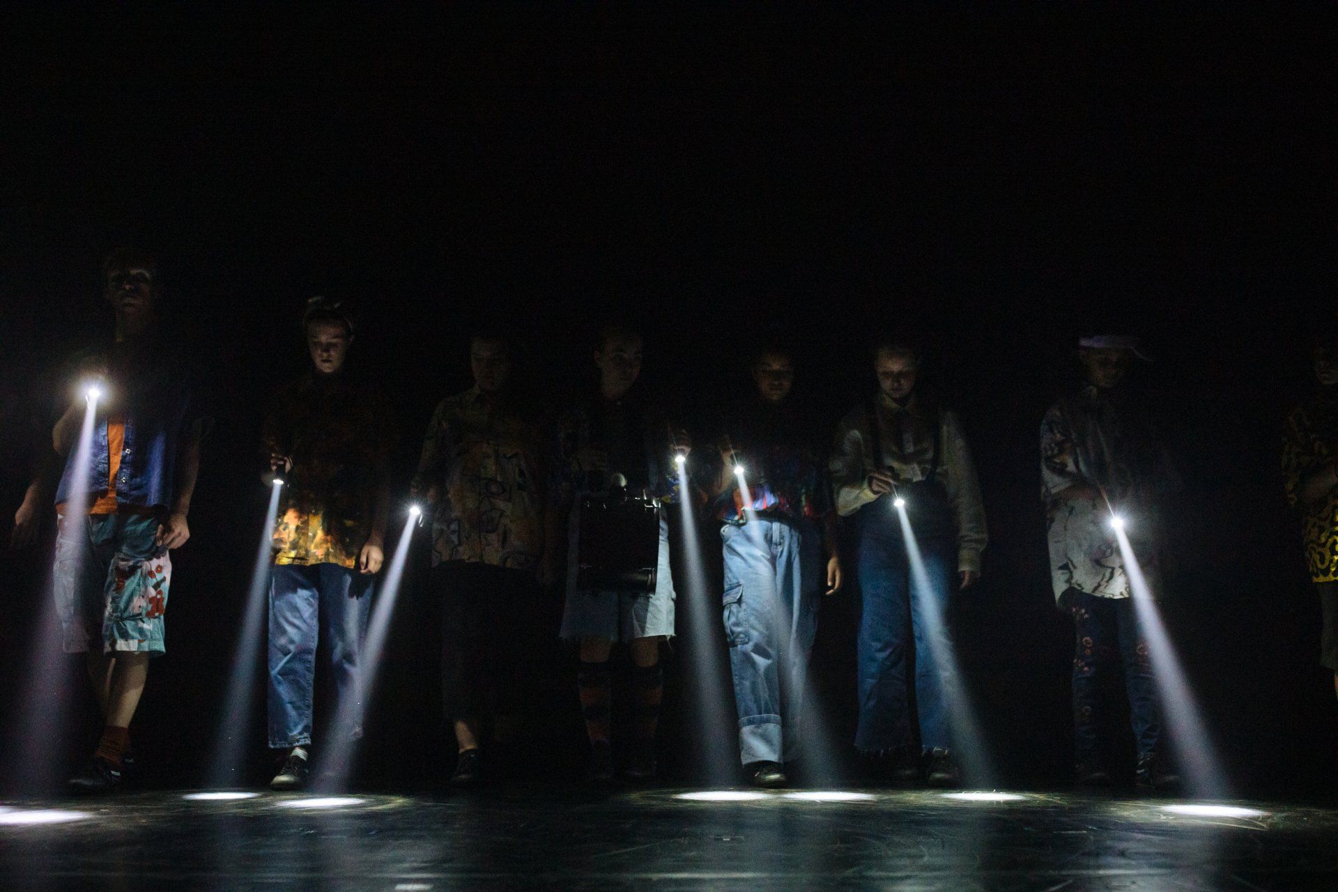 a group of people are standing in the dark holding flashlights .