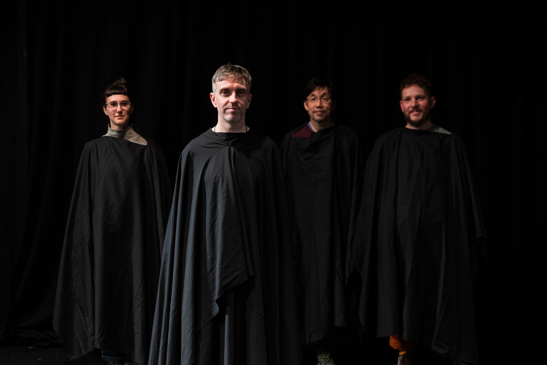 A group of people are standing next to each other in black cloaks.
