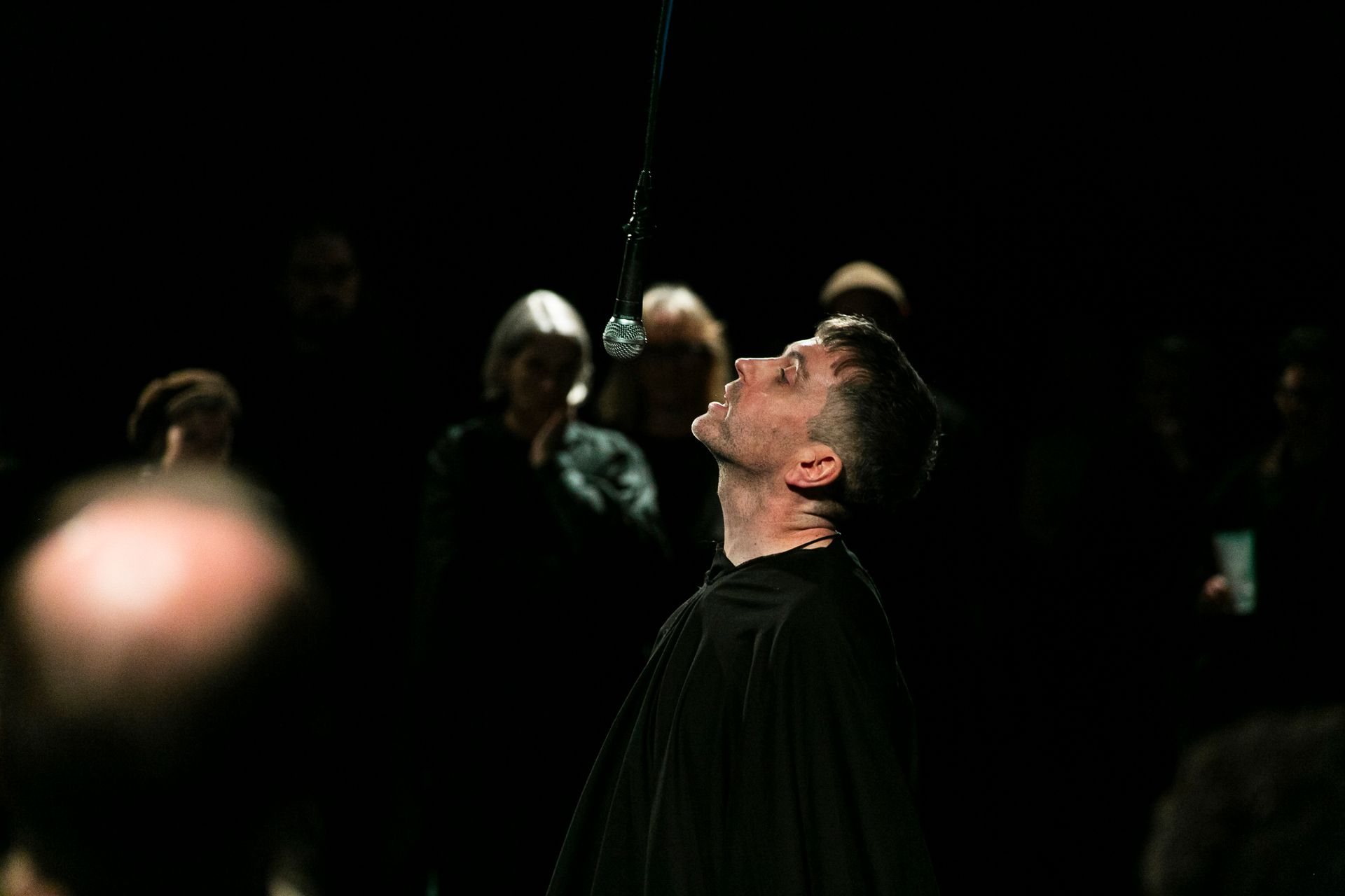 A man is speaking into a microphone in a dark room.