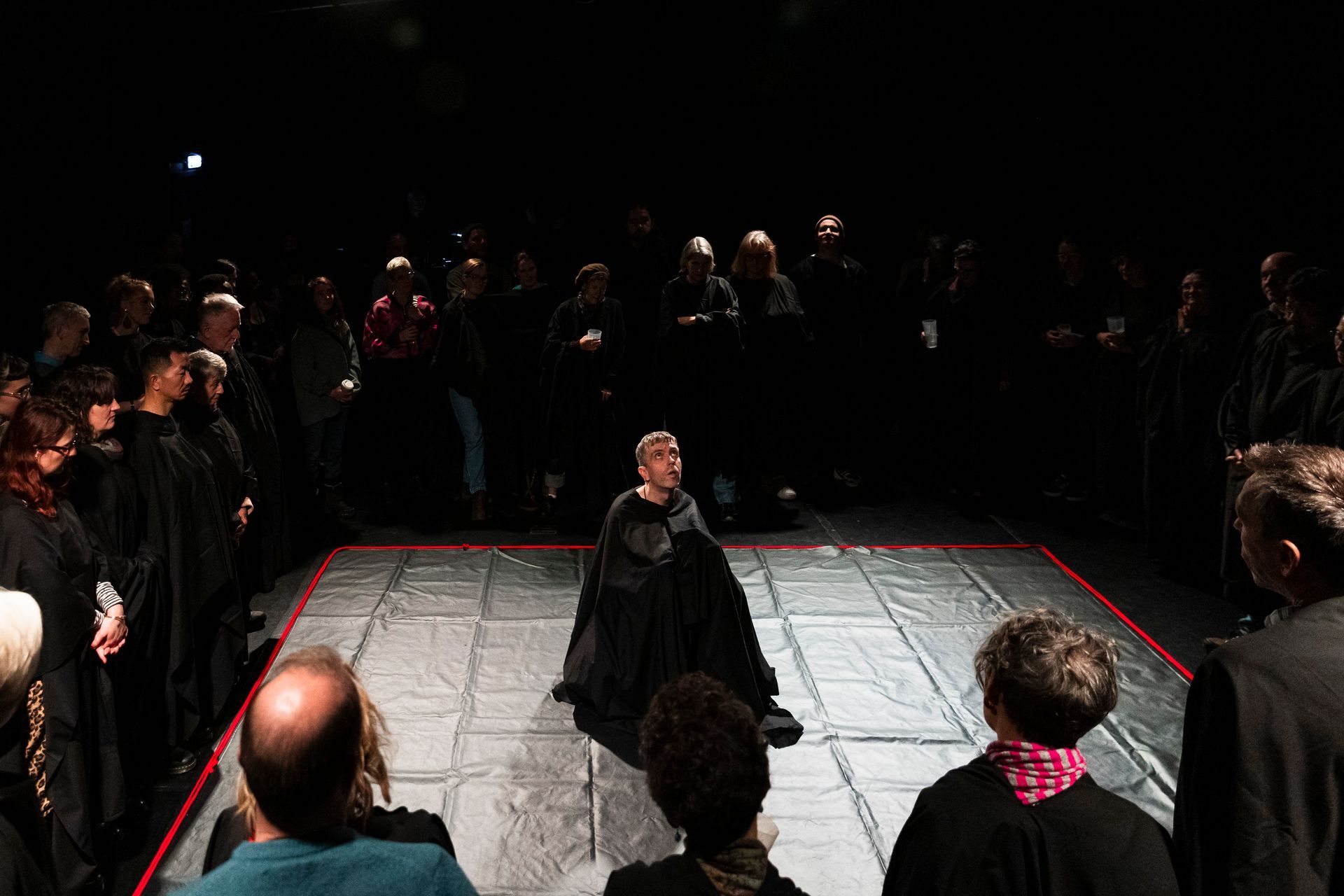 A group of people are standing around a stage in a dark room.