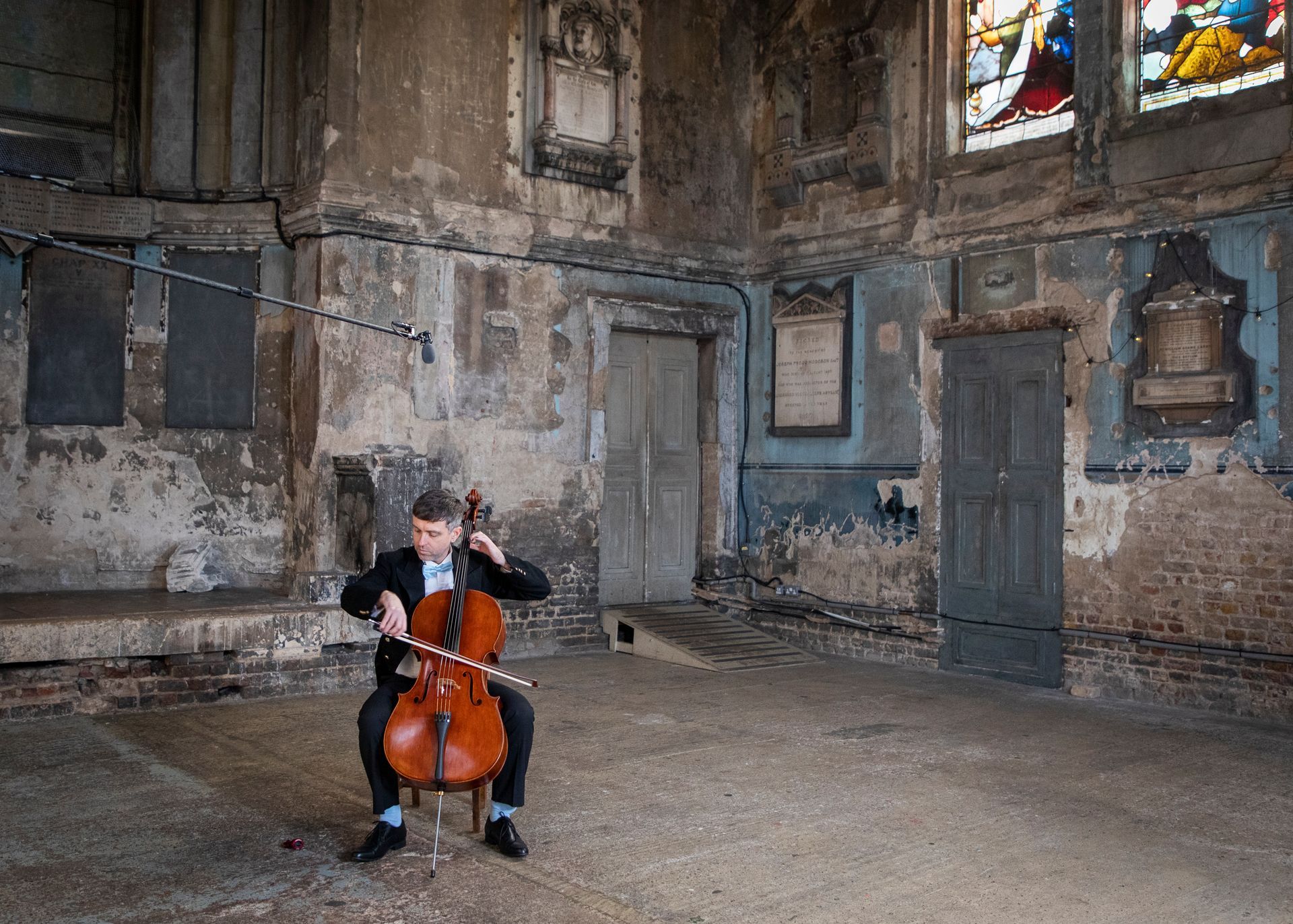 a man is playing a cello in an empty church .