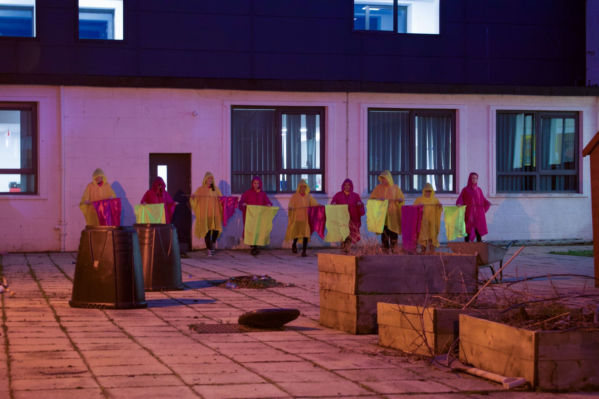 A group of people are standing in front of a building holding flags.