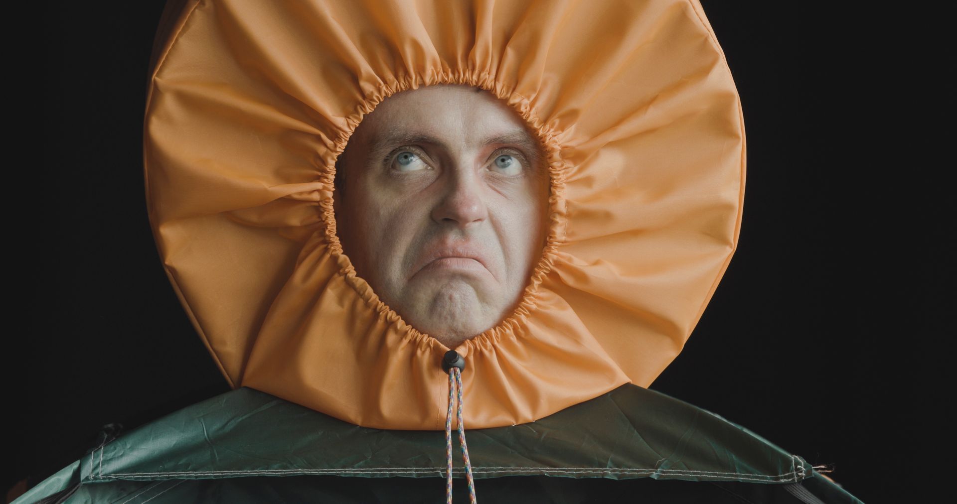 A man is wearing a large orange hat on his head.