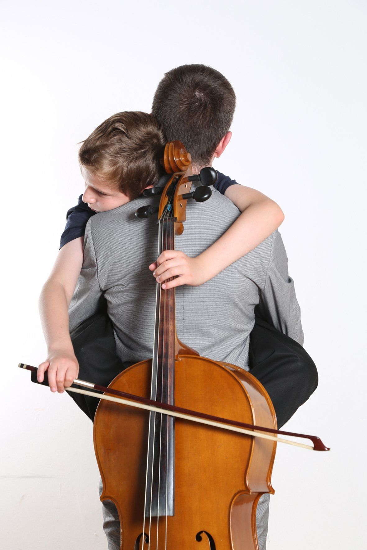 a man carrying a child on his back while playing a cello