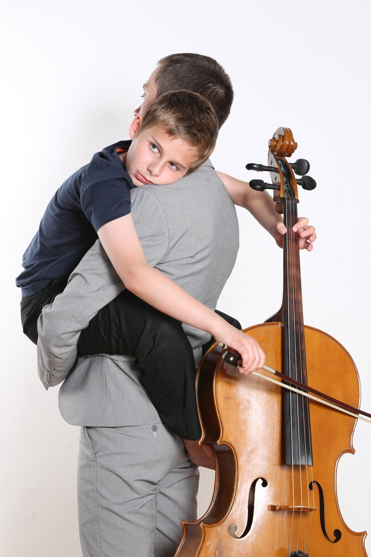 a man is holding a child who is playing a cello .