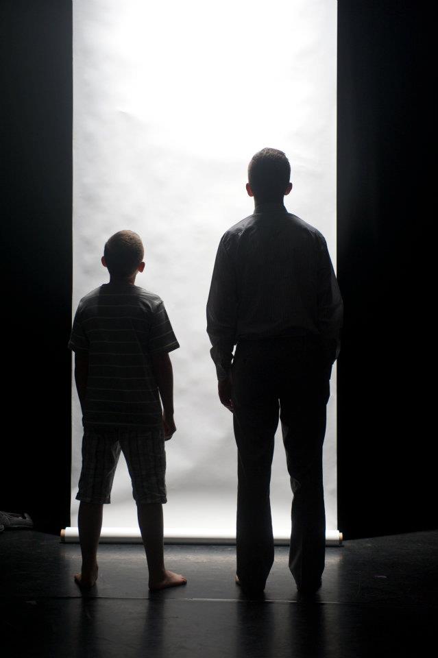 a man and a boy are standing in front of a white wall .