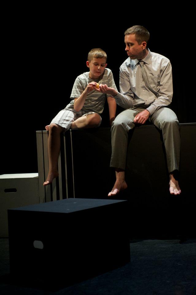a man and a boy are sitting on a box on a stage .