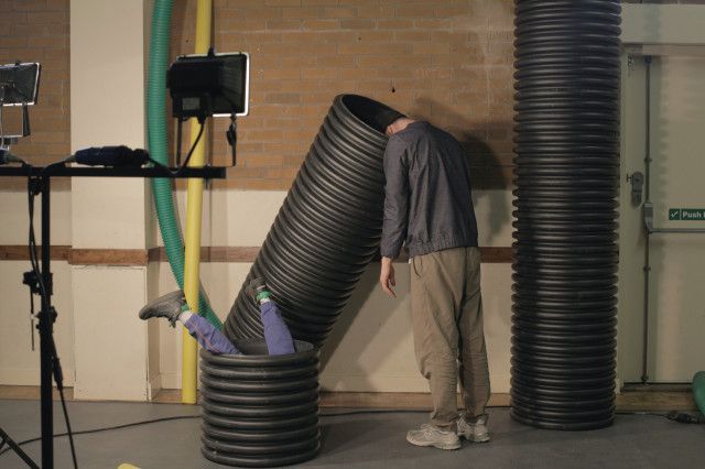 a man is standing next to a large pipe with his head in it