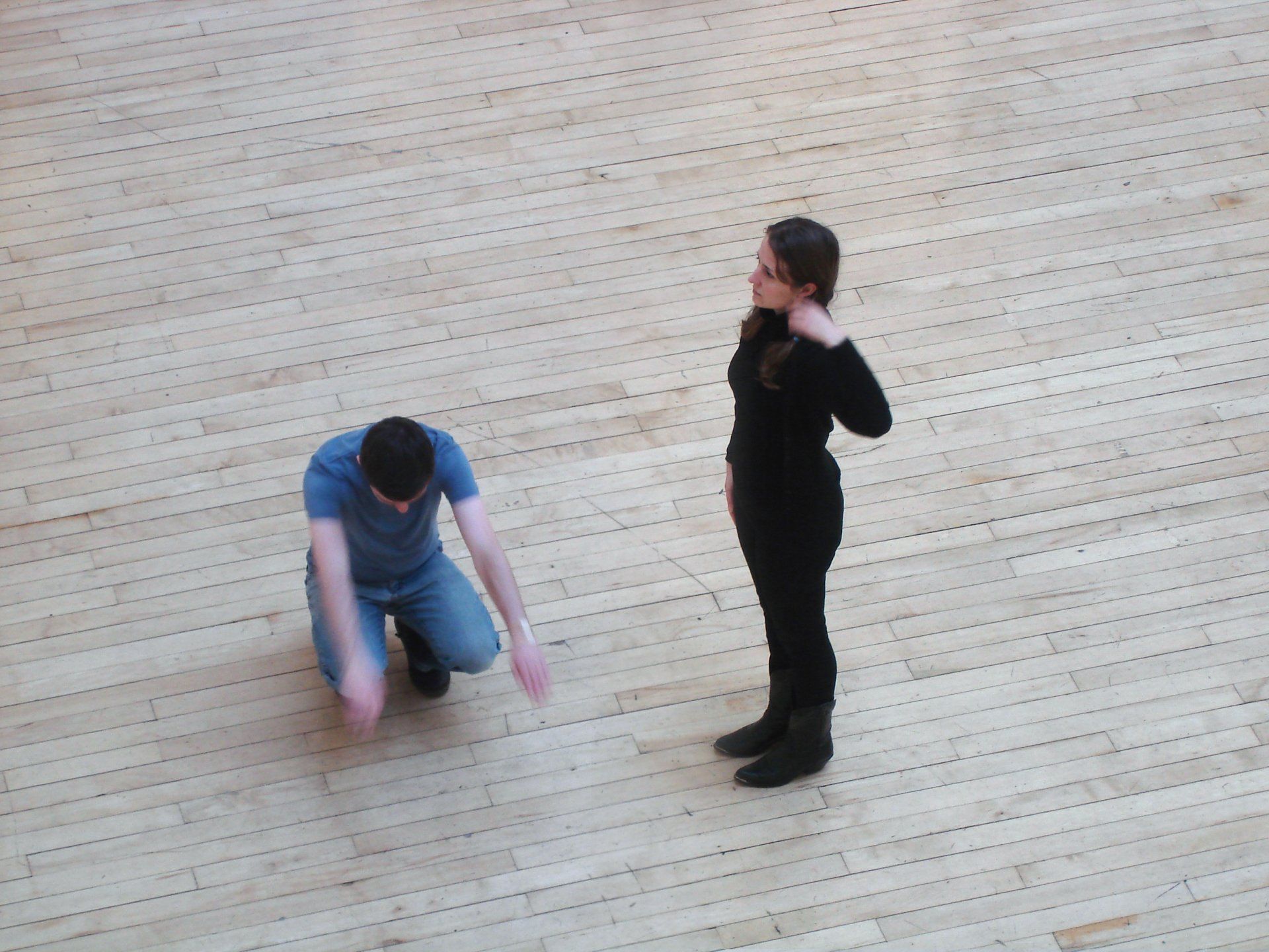 a man and a woman are standing on a wooden floor