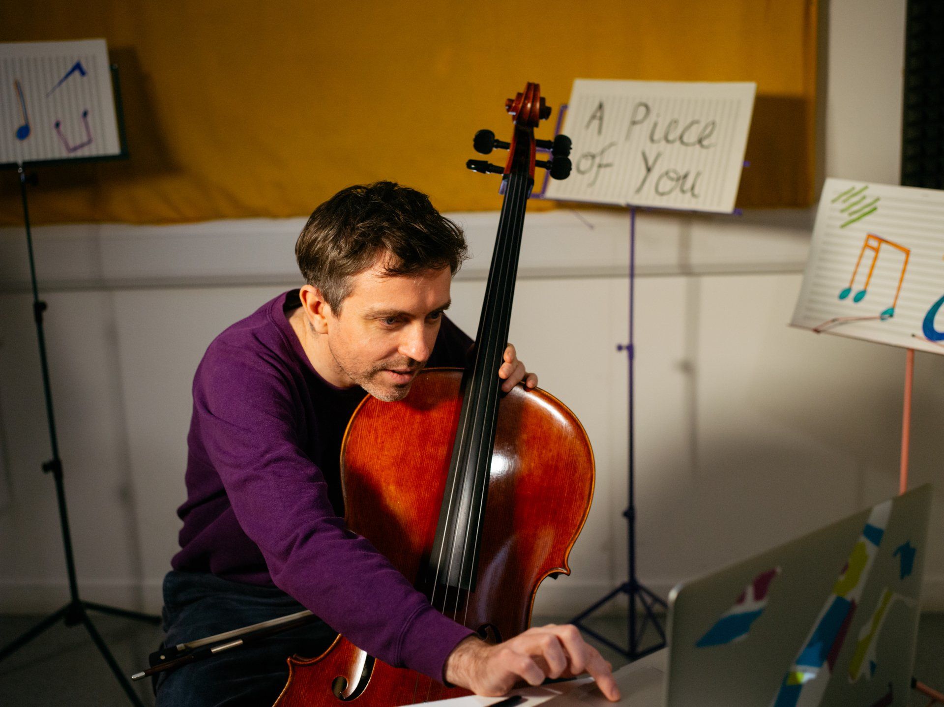 a man is playing a cello in front of a sign that says a piece of you