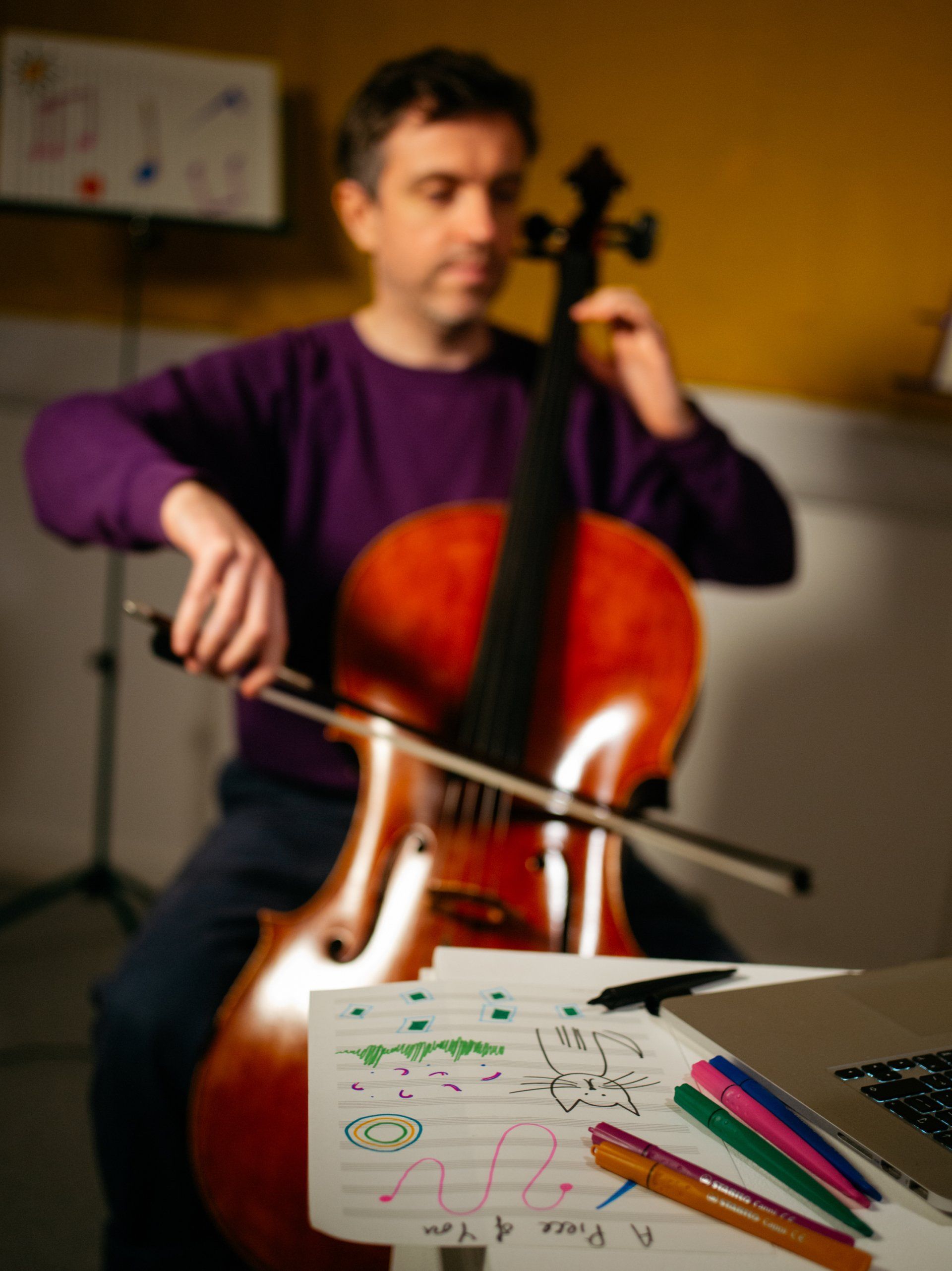 a man in a purple shirt is playing a cello