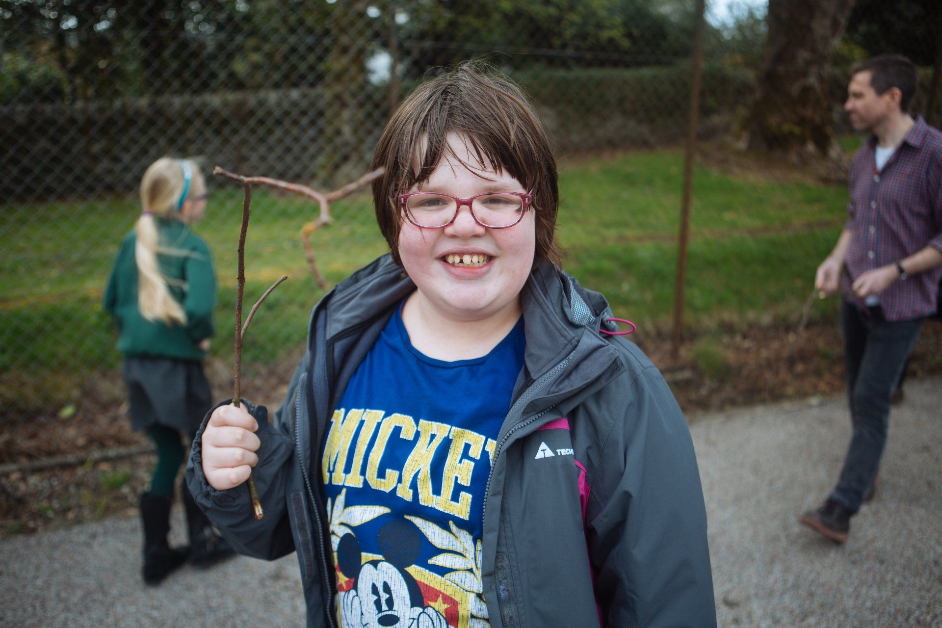 a young girl wearing a mickey mouse shirt is holding a stick in her hand .