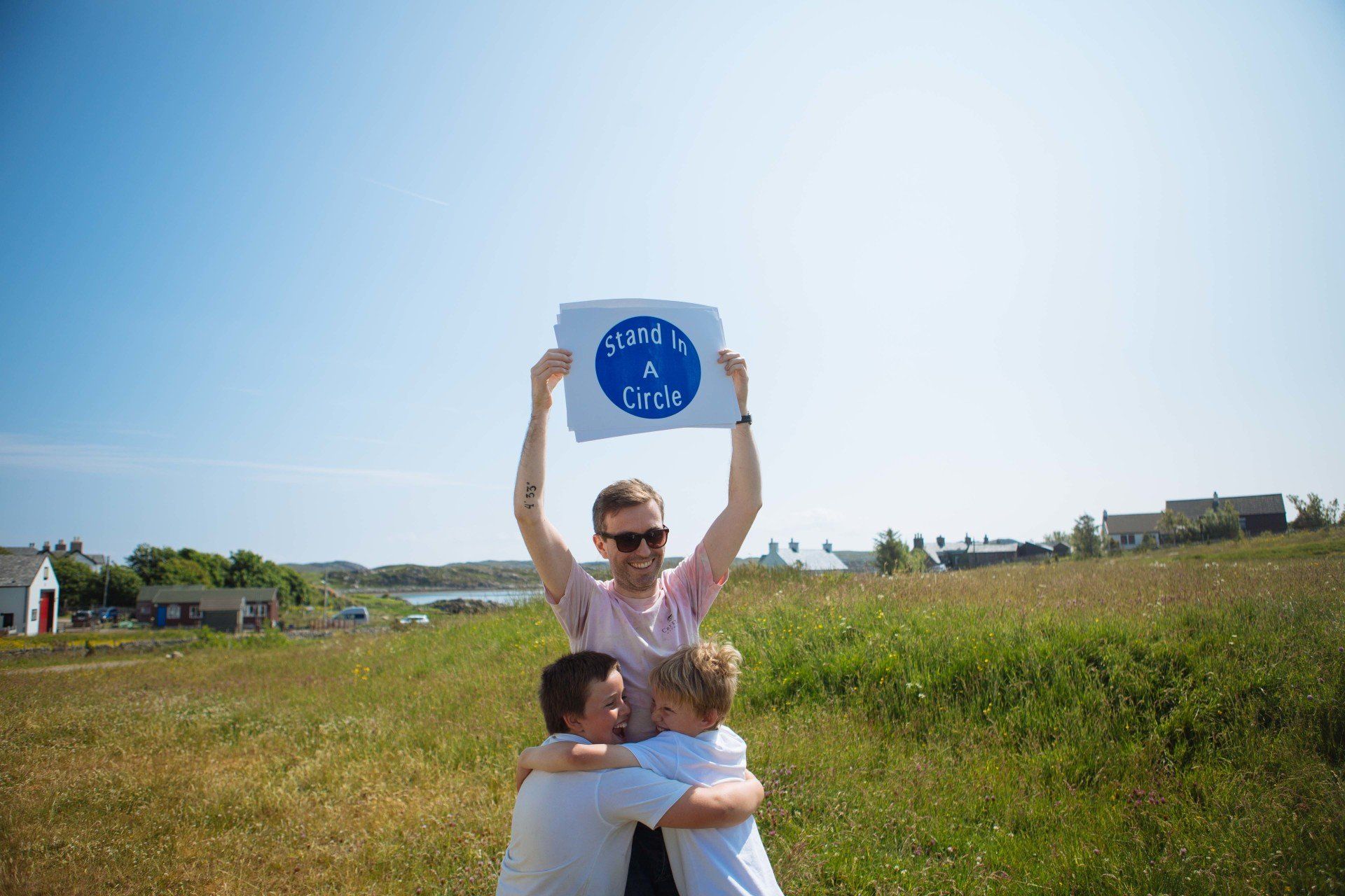 a group of people are hugging and holding a sign in a field .