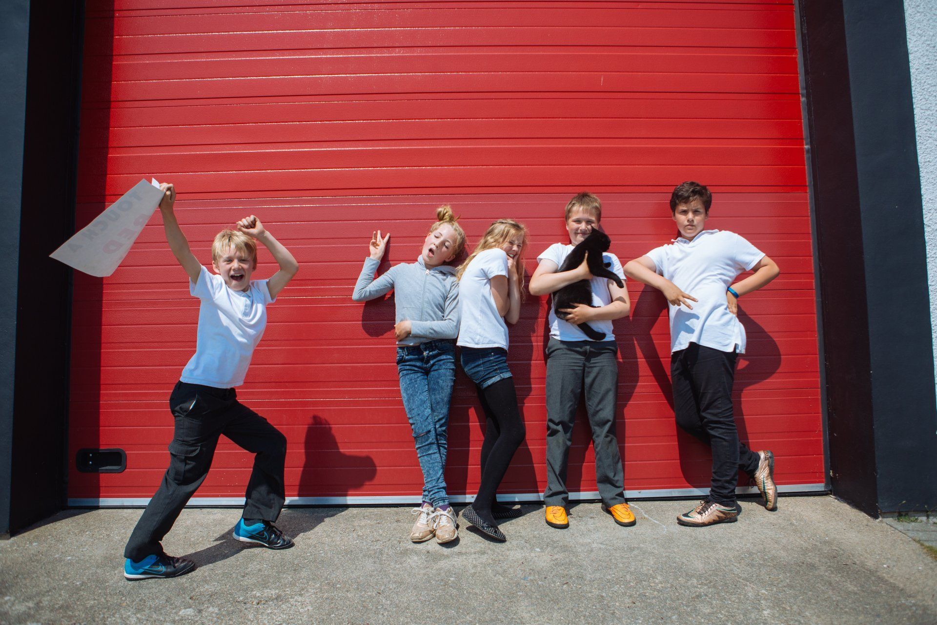 a group of children are posing for a picture in front of a red garage door .