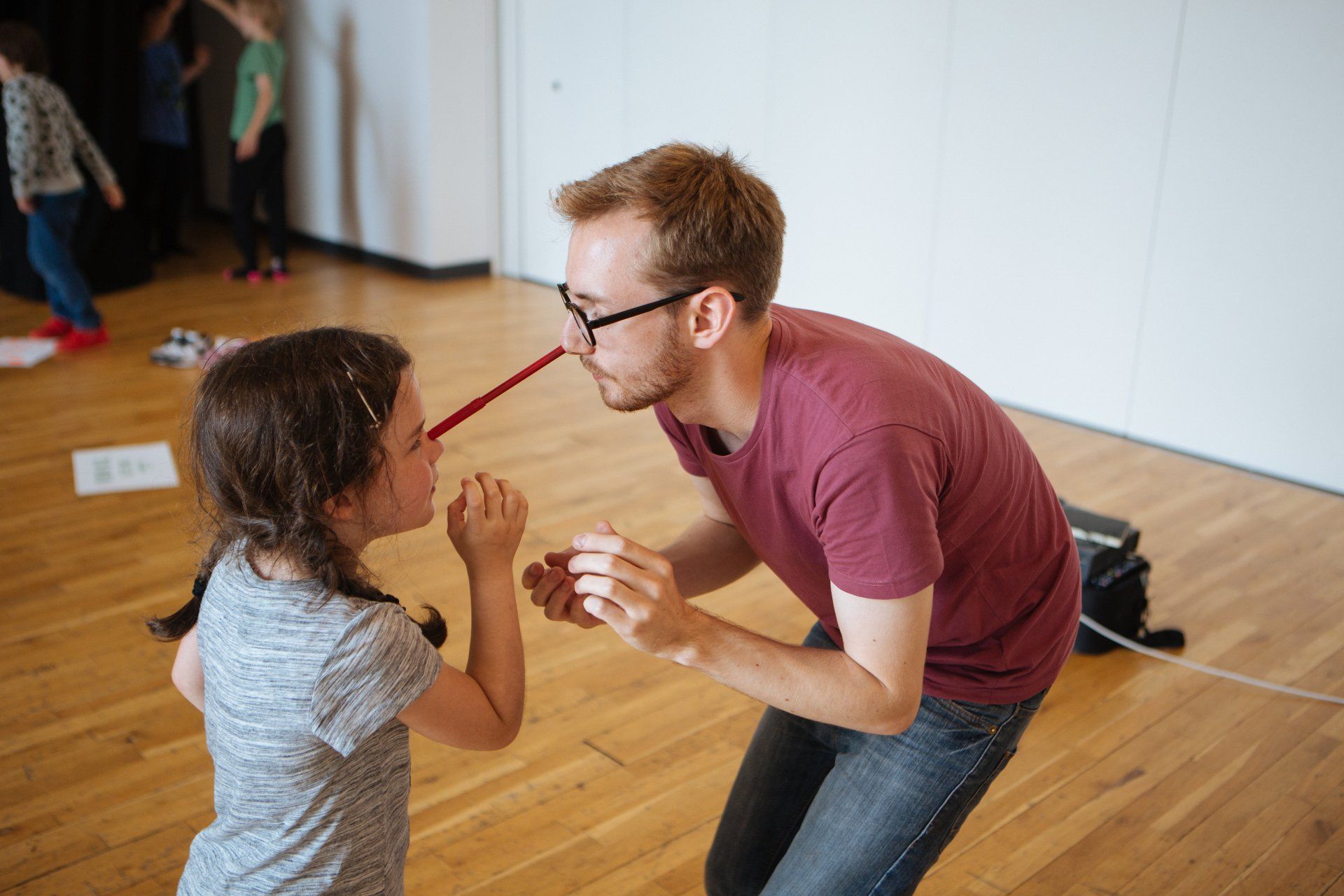 a man and a little girl are playing with a red pencil .