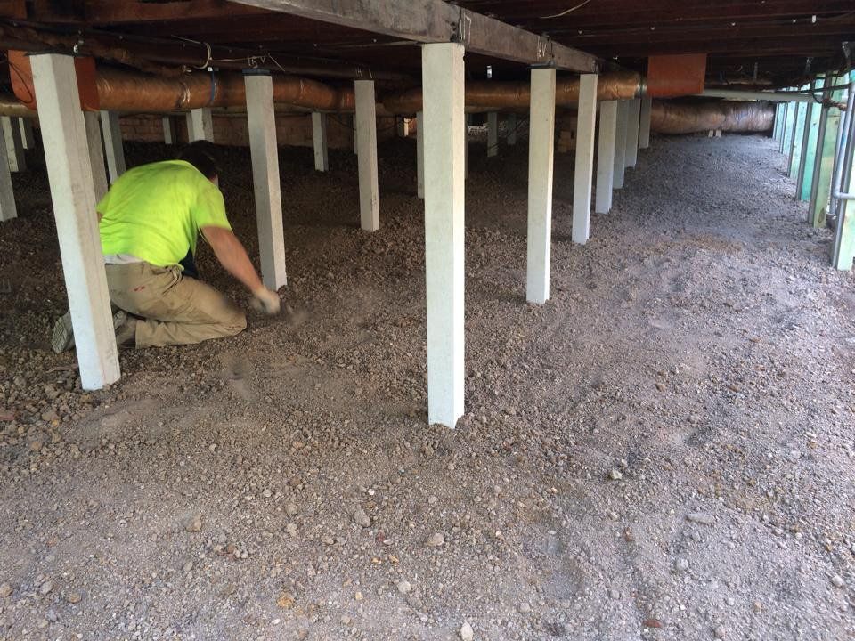 A Man is Kneeling on the Ground Under a House — Melbourne, VIC — Special Reblocking Services