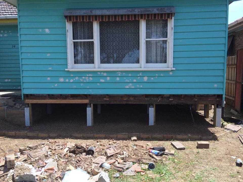 A Blue House With a White Window is Sitting on Stilts — Melbourne, VIC — Special Reblocking Services