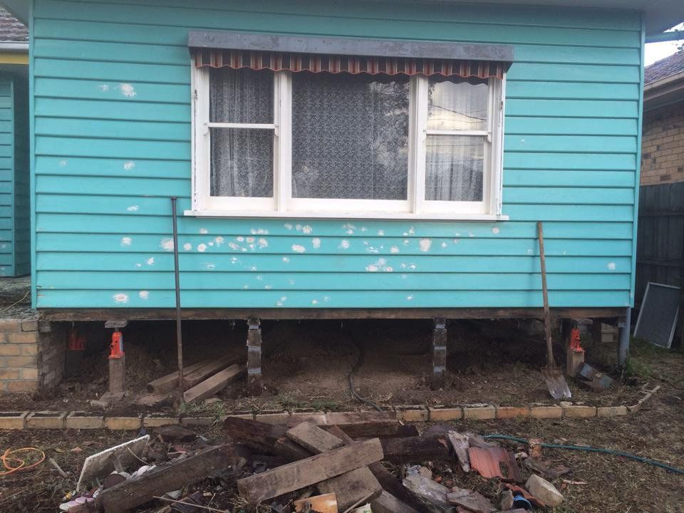 A Blue House With a Window and a Pile of Wood in Front of It — Melbourne, VIC — Special Reblocking Services