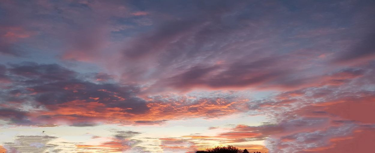Sonnenuntergangshimmel mit Wolken in Rosa-, Orange- und Violetttönen.