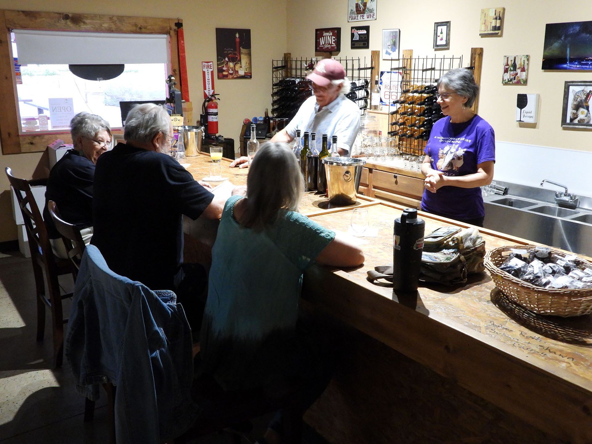 Man pouring wine sample to group with wife next to him.