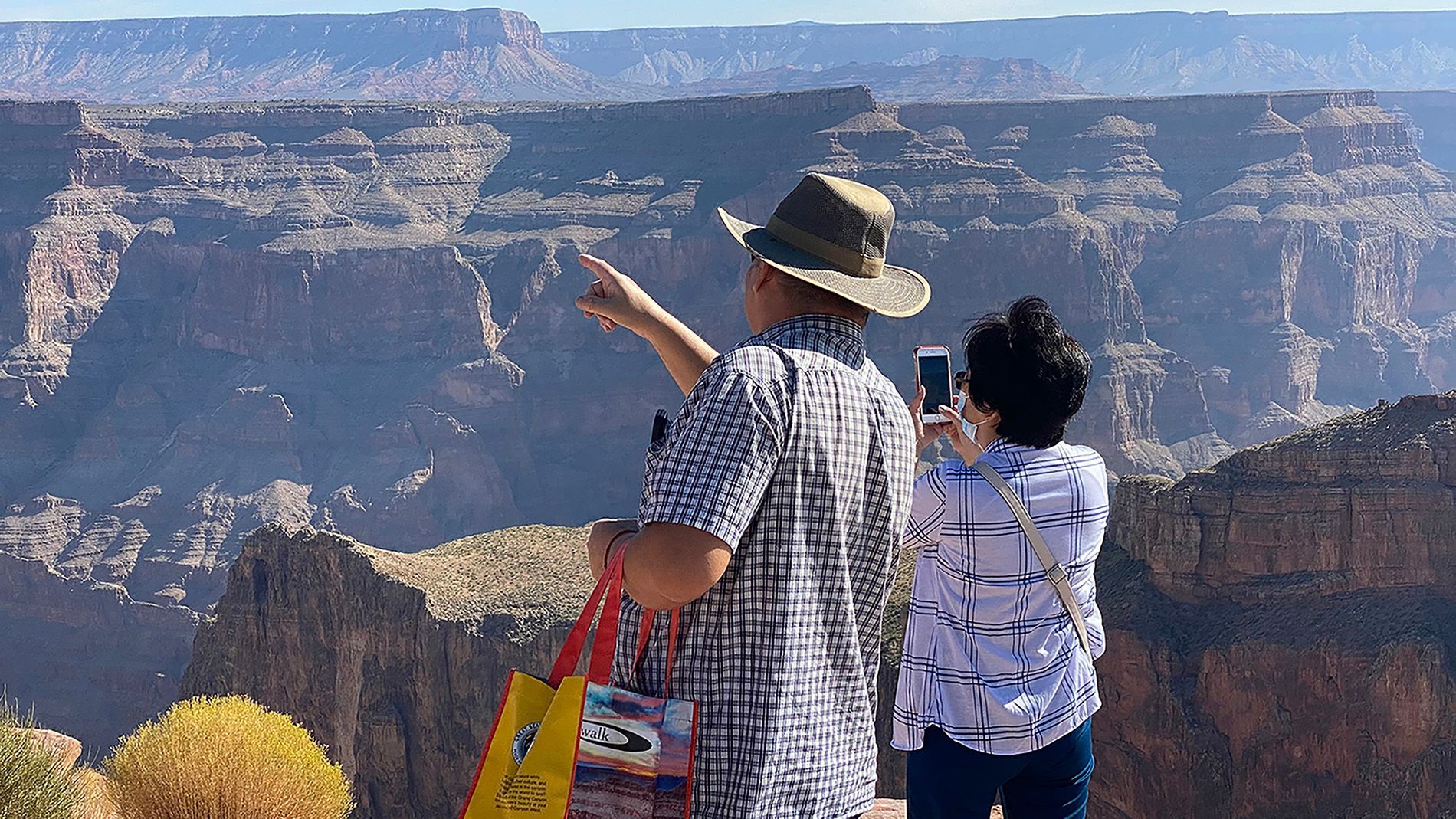 A man and a woman are taking a picture of the grand canyon.