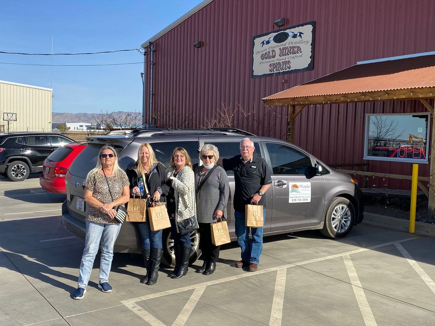 Group holding bags at distillary.