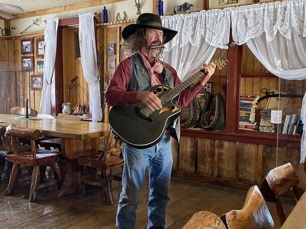 A man in a cowboy hat is playing a guitar in a room.