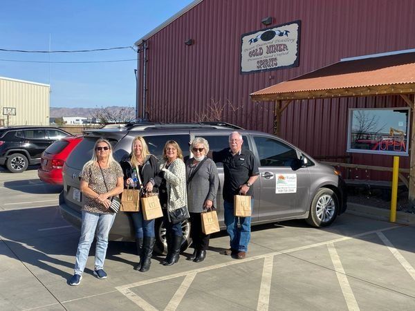 A group of people are standing in front of a van in a parking lot.