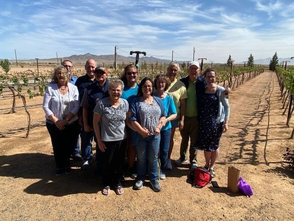 A group of people posing for a picture in a vineyard