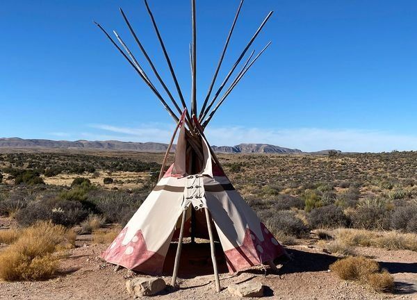 A teepee in the desert with mountains in the background