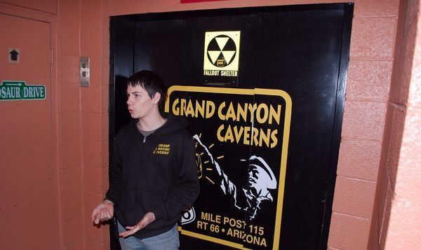 A man standing in front of a sign that says grand canyon caverns