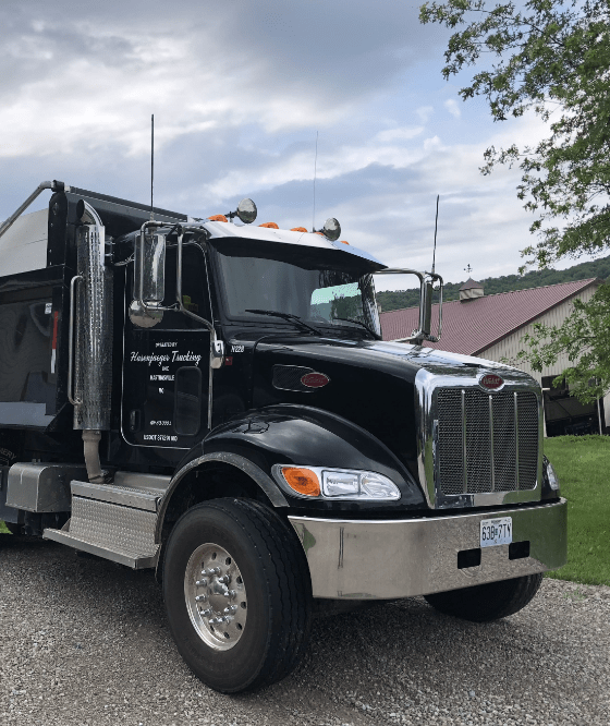 A black dump truck is parked on a gravel road.