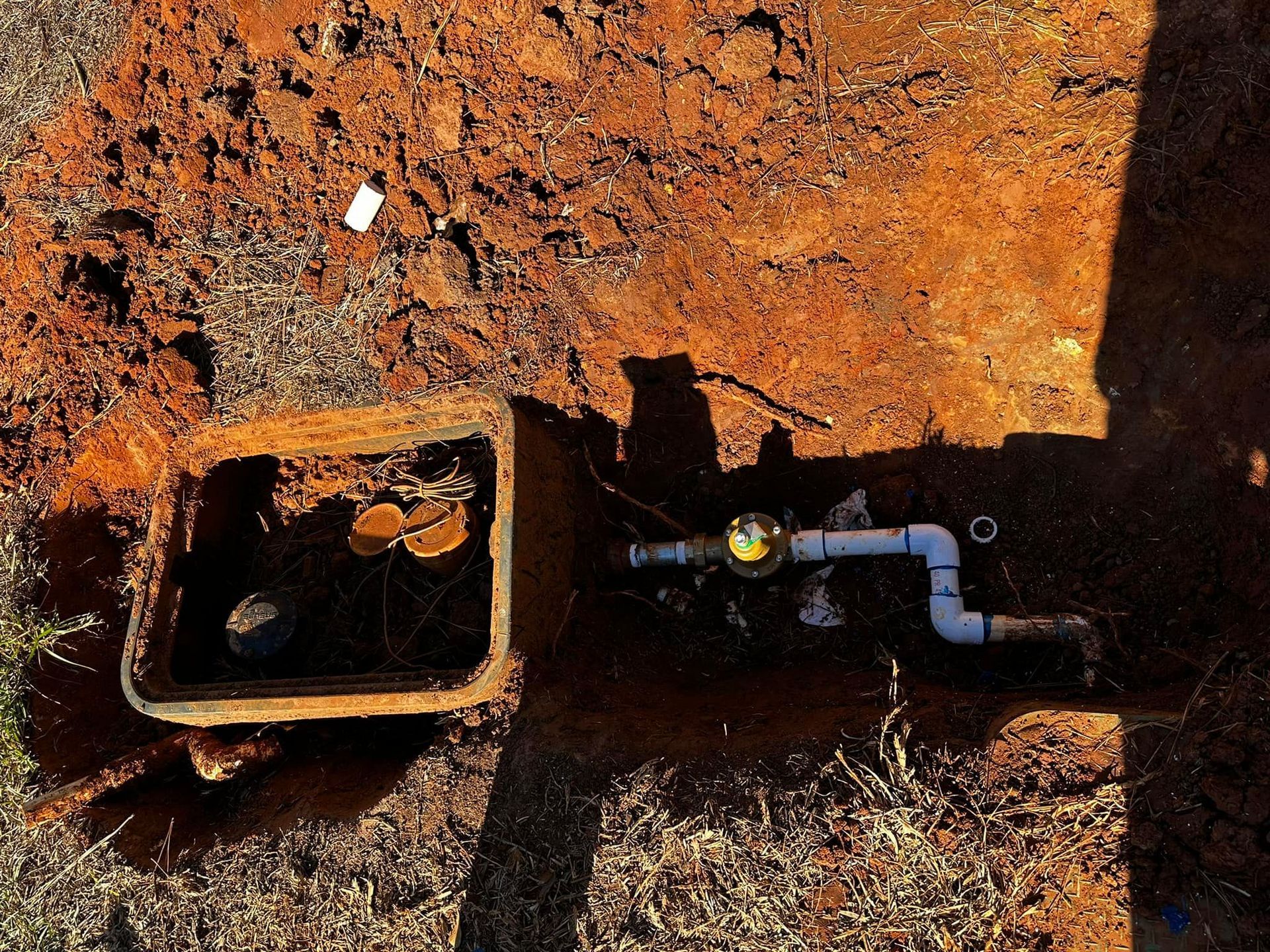 A water meter is sitting in the dirt next to a box