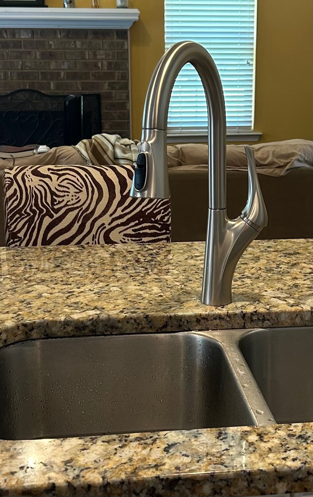 A kitchen sink with a stainless steel faucet on a granite counter top.