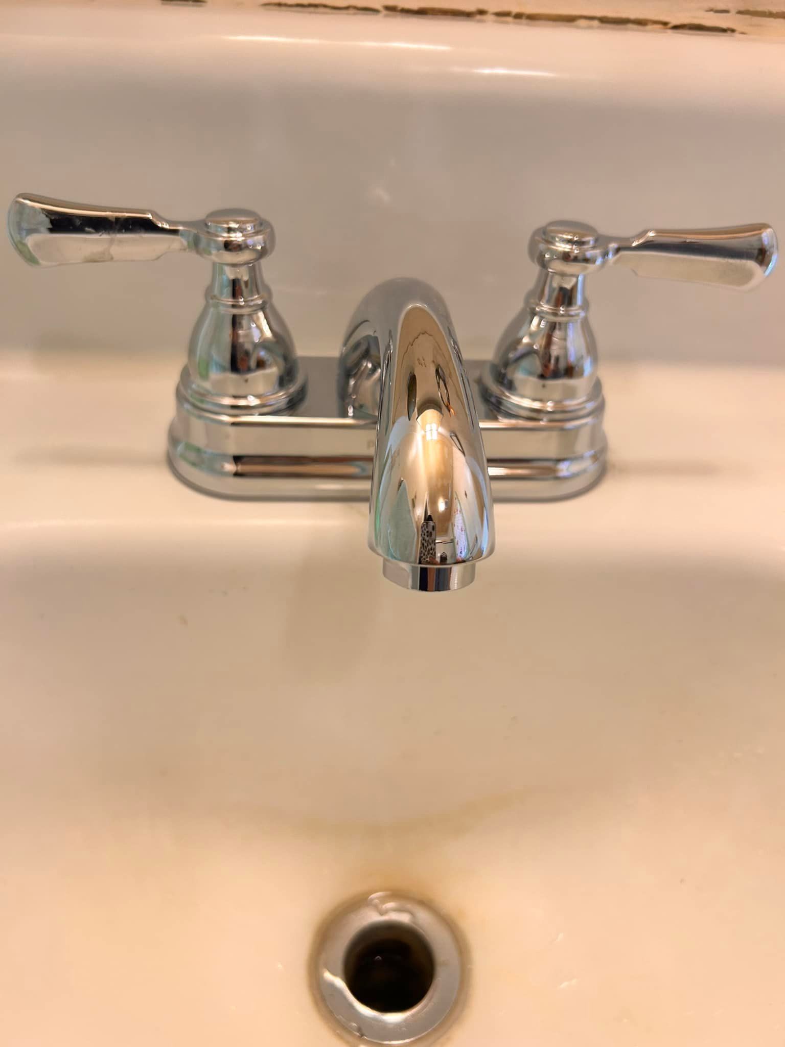 A bathroom sink with a chrome faucet and two handles