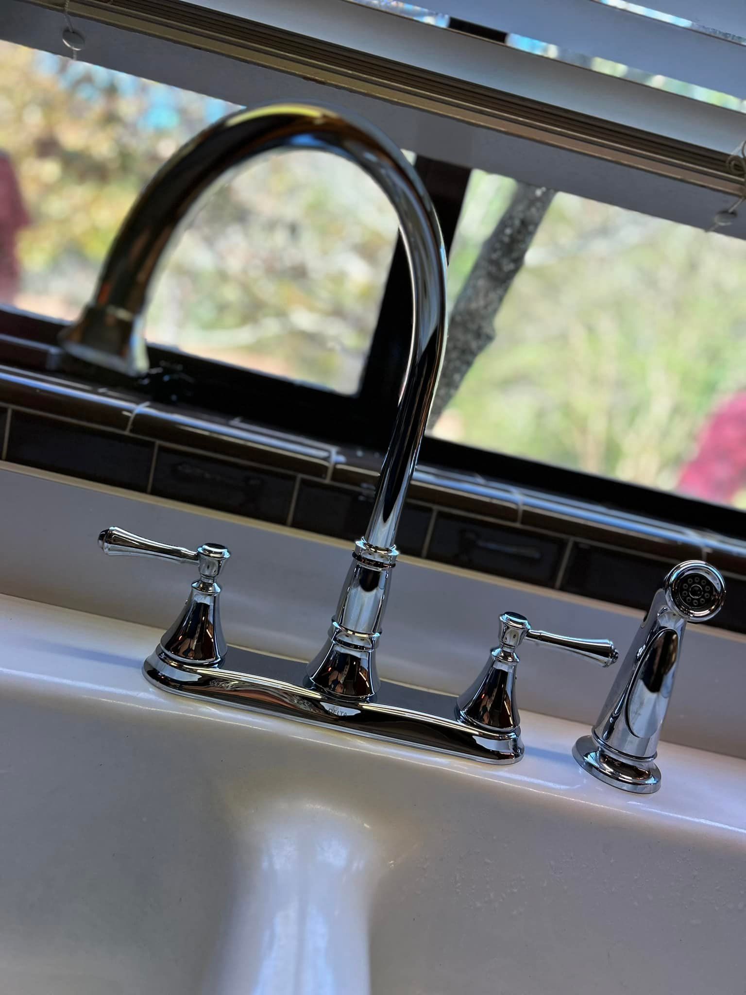A kitchen sink with a chrome faucet and a window in the background
