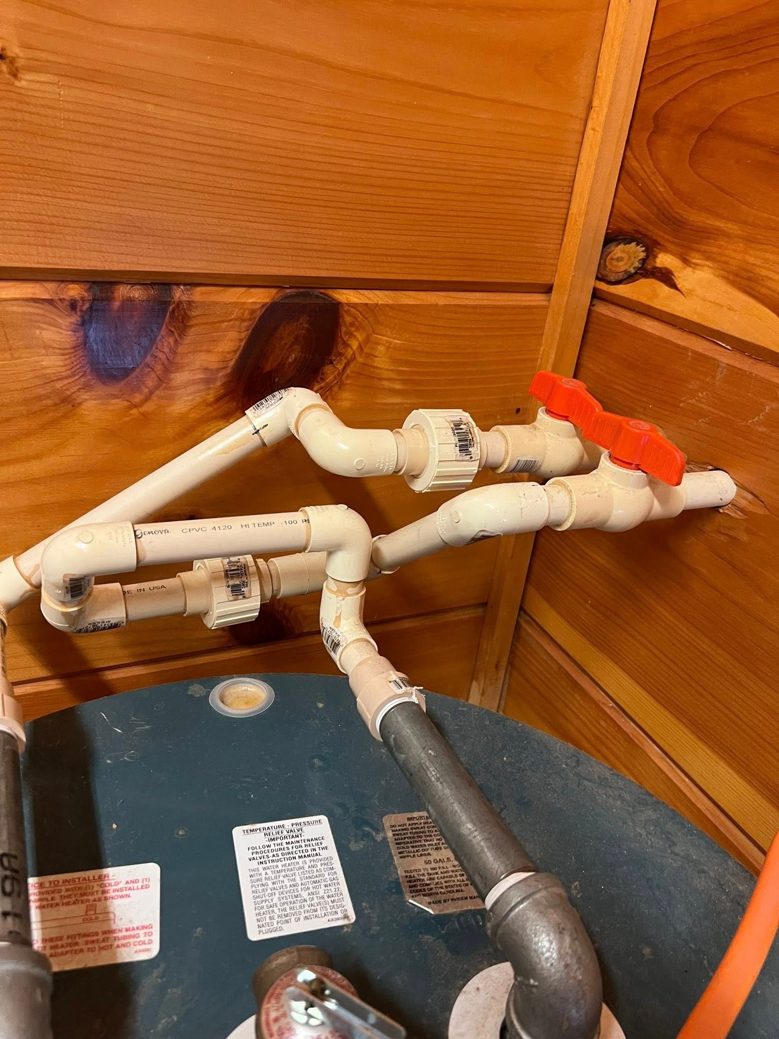 A close up of a water heater with pipes attached to it.