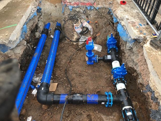 A plumber is working on a pipe in a room.