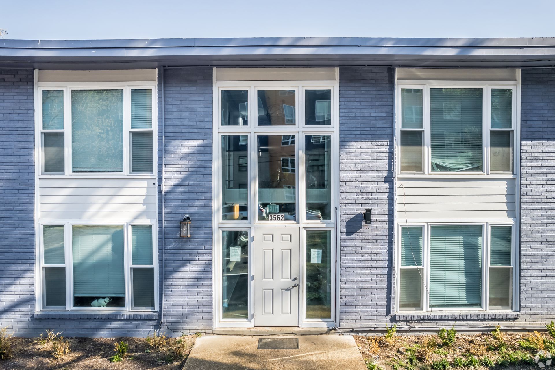 Blue building with white-trimmed windows and a central glass door, front view.