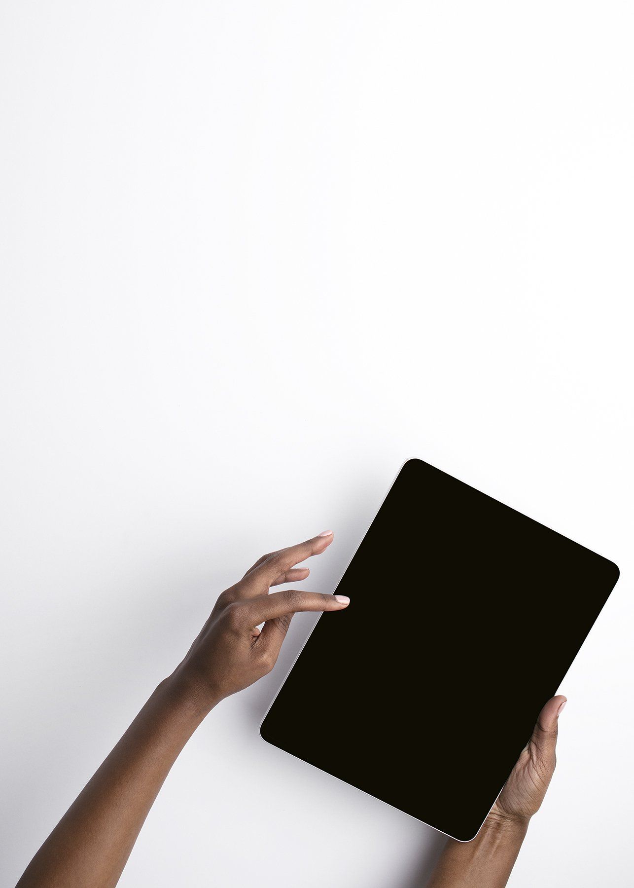 Person holding a black tablet, touching the screen with one finger, against a white background.