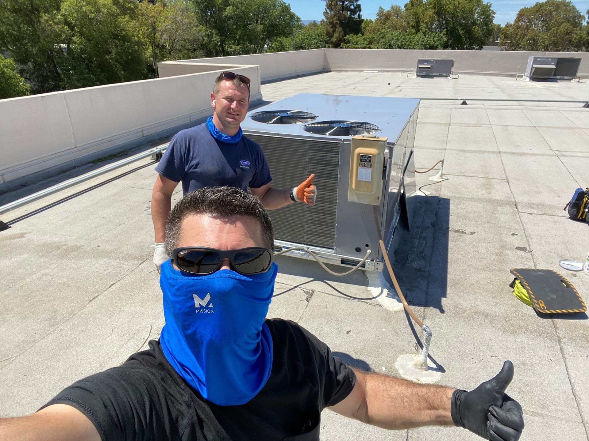 a man wearing a blue mask is standing on a roof next to another man .