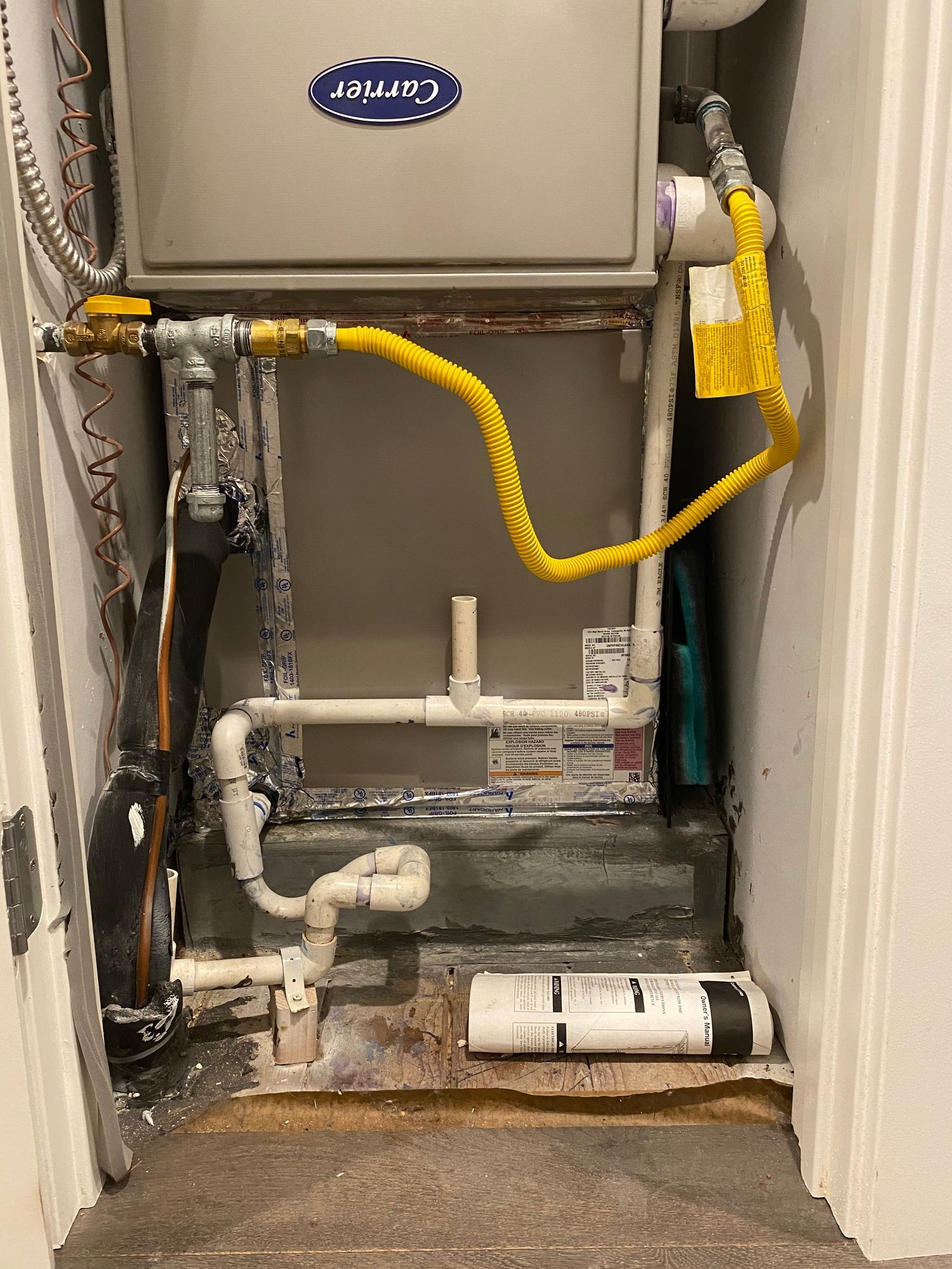 a carrier air conditioner is sitting in a closet next to a door .