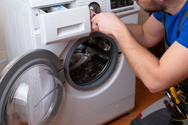a man is fixing a washing machine in a bathroom .